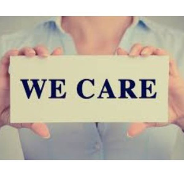 Person holding a sign that says 'WE CARE'.