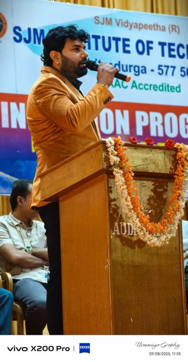 Man in brown jacket speaking at a podium during an event.