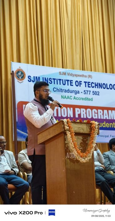 Man speaking at a podium during an event at SJM Institute of Technology.