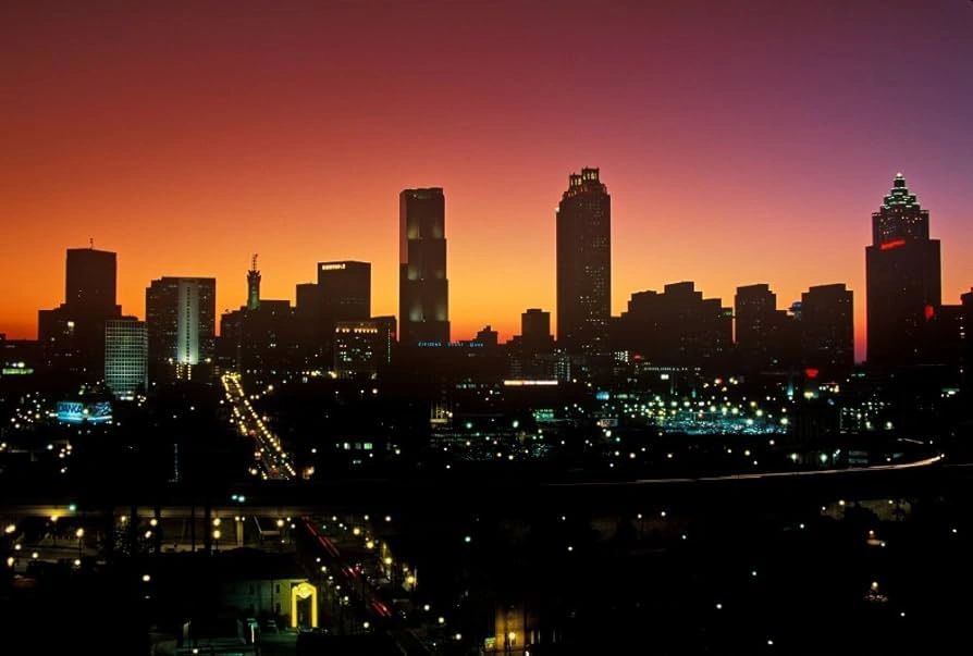 City skyline at sunset with illuminated buildings and streets.