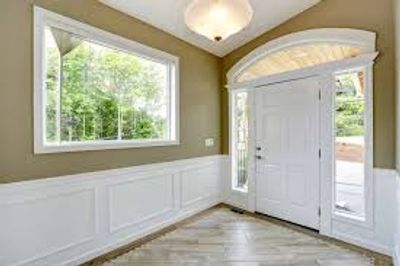 Bright entryway with large windows and white door.