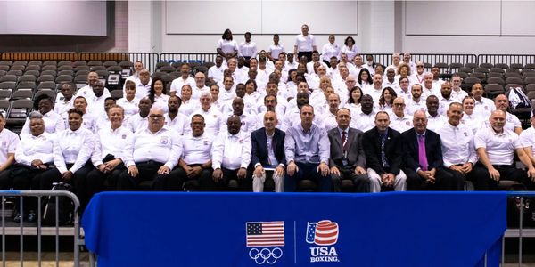 Group photo of USA Boxing team and officials in white shirts and suits.