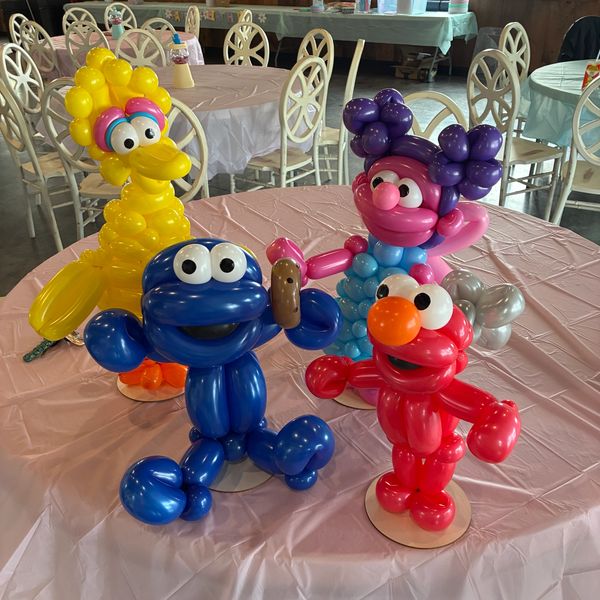Balloon sculptures of Sesame Street characters on a table.