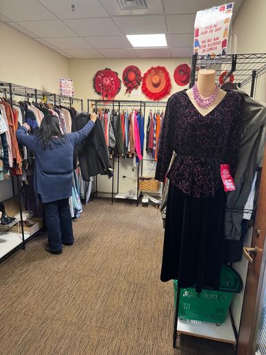 A shopper pulling out an article of women's clothing that she might like to buy at the Center's New