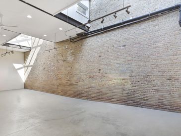 Empty industrial-style room with exposed brick wall and skylight.