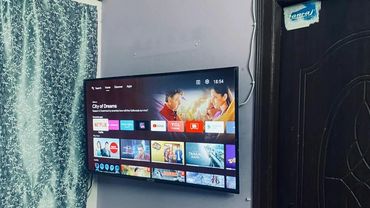 Wall-mounted smart TV displaying various streaming apps and shows.