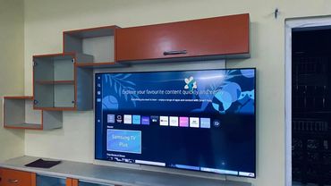 Modern TV setup with wall-mounted shelves and Samsung Smart Hub interface.