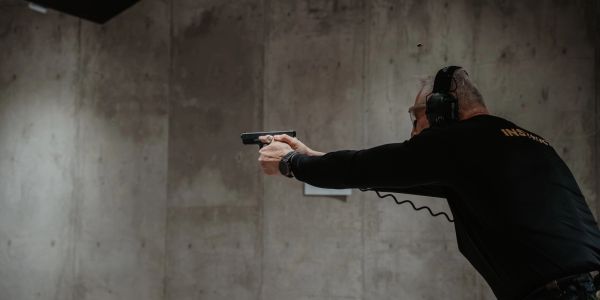 Man practicing shooting at an indoor gun range wearing ear protection.