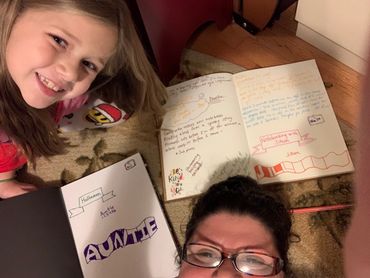 Michelle Haseltine and her niece laying on the group surrounded by our two notebooks.
