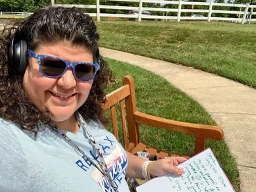 Michelle Haseltine sitting on a beanch showing the notebook on her lap