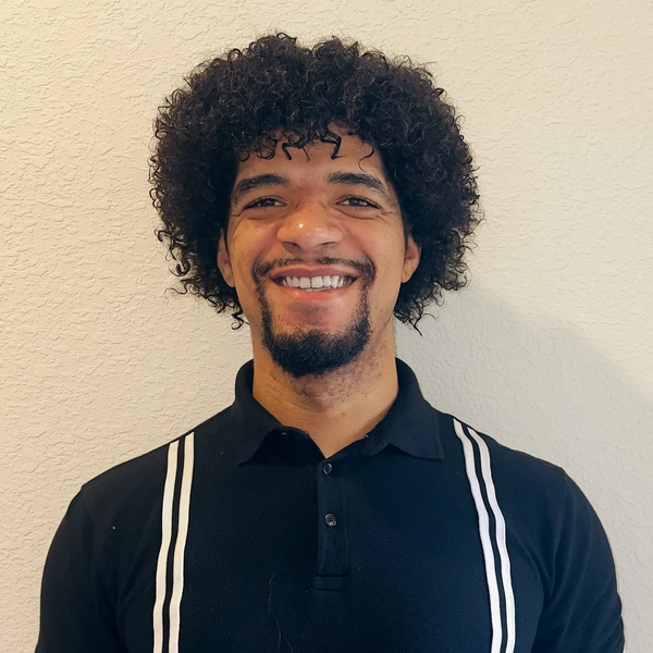 Smiling man with curly hair wearing a black shirt with white stripes.