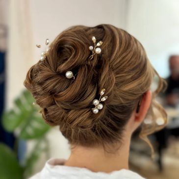 Elegant updo hairstyle adorned with pearl and gold accessories.