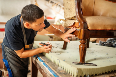 A craftsman restores an antique chair with care using a screwdriver.