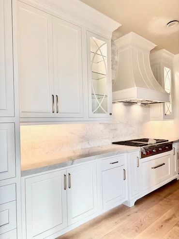 custom white kitchen cabinetry with inset doors and custom stove hood