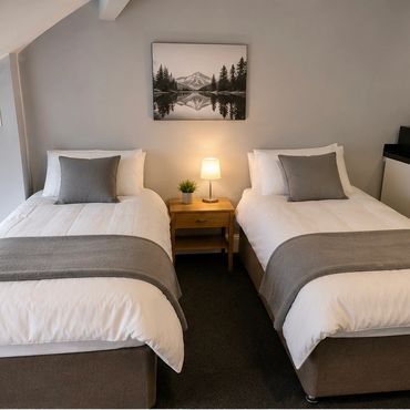 Neatly arranged twin beds in a cozy, modern room with neutral decor.