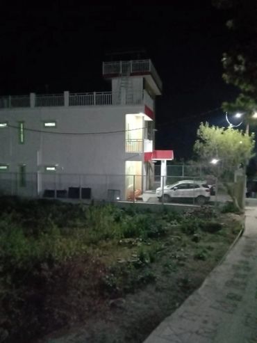 A white building illuminated at night with cars parked nearby.