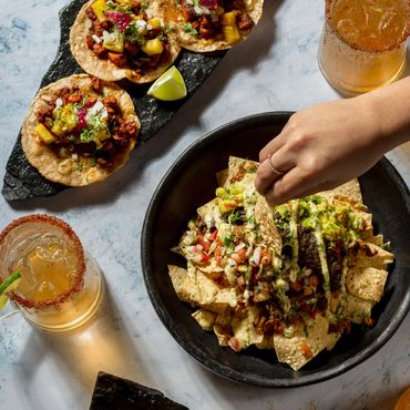 Irresistibles nachos, tacos y micheladas sobre la mesa para compartir con amigos