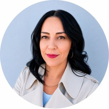 Woman with black hair and a beige coat against a blue background.