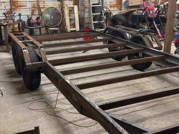 A metal trailer frame under construction in a workshop.
