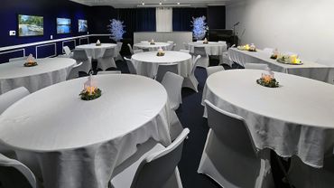 Elegant event room with round tables, white tablecloths, and soft candle lantern centerpieces.