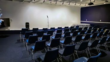 Empty conference room with rows of chairs and a microphone stand.