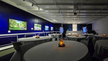 Elegant event room with round tables and warm lantern centerpieces.