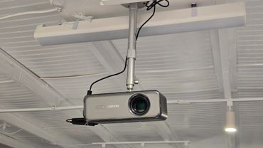 Ceiling-mounted projector with cables attached in a modern room.