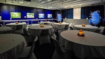 Elegant banquet room with round tables, white linens, and warm lantern centerpieces.