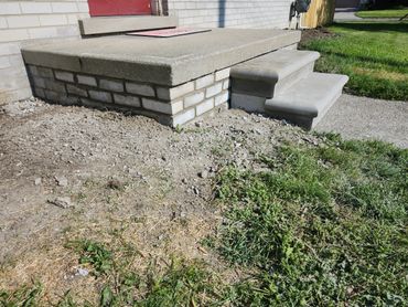 Concrete steps and porch with surrounding dirt and grass.