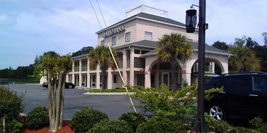 Exterior view of a hotel with palm trees and parked cars.