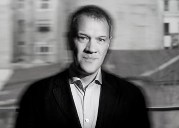 Black and white portrait of a man with a blurred background.