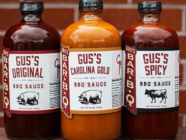 Three bottles of Gus's BBQ sauces: Original, Carolina Gold, and Spicy.