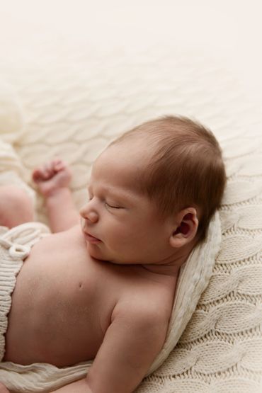 Sleeping newborn baby resting peacefully on a knitted blanket.