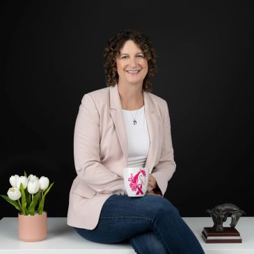 Smiling woman sitting with a coffee mug and flowers.