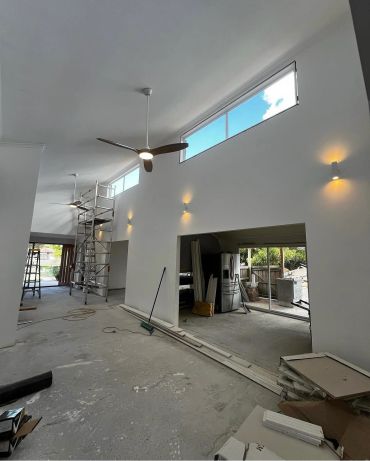 Spacious modern room under renovation with high ceilings and ceiling fans.