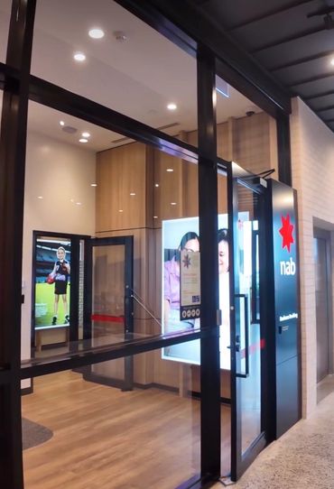 Entrance of a modern NAB bank branch with glass doors and wooden interior.