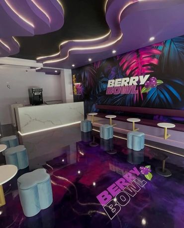 Modern cafe with purple lighting and berry-themed decor.