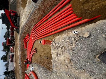 Construction site with orange pipes being installed underground.
