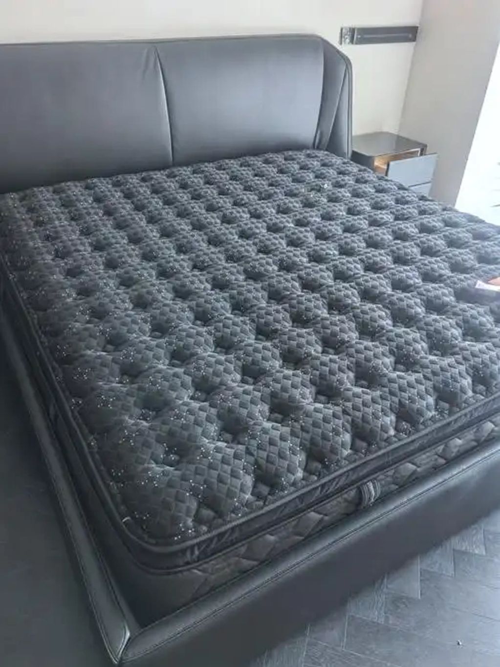 Luxurious black mattress on a sleek leather bed frame.
