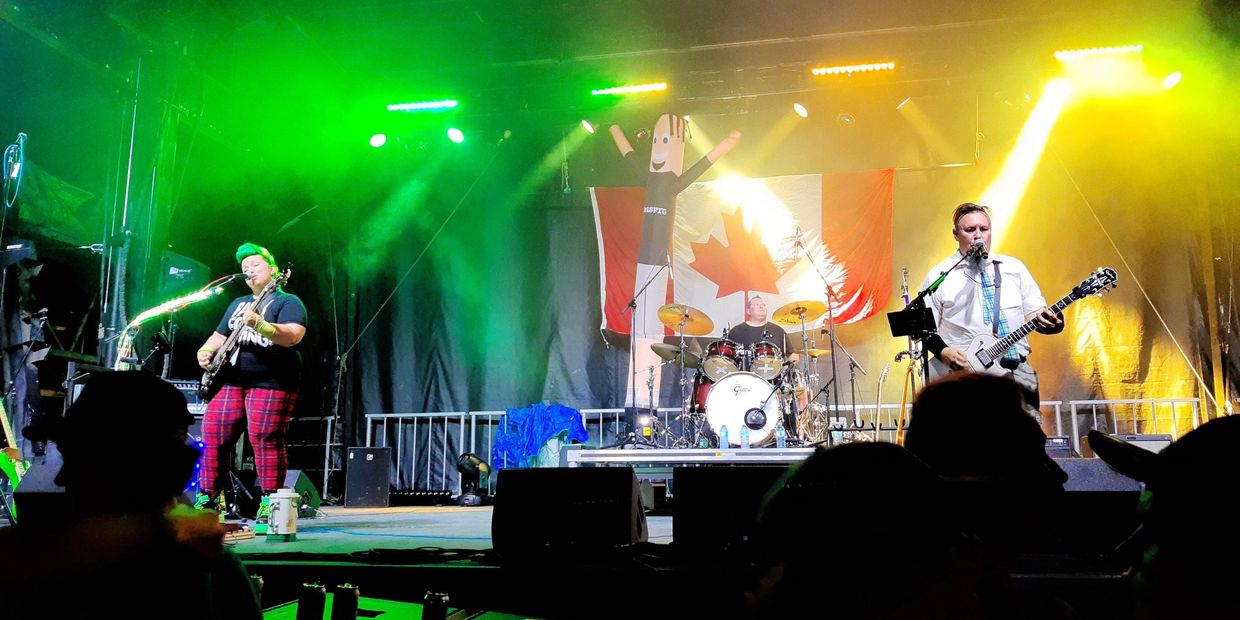 Live band performing on stage with Canadian flag and vibrant lighting.