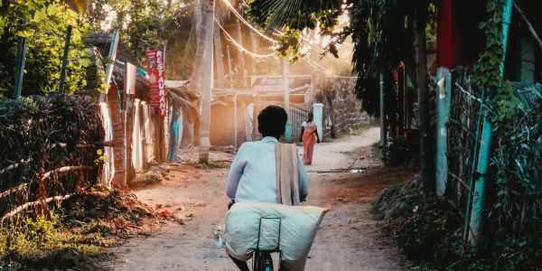Person riding bicycle on a sunlit rural path.