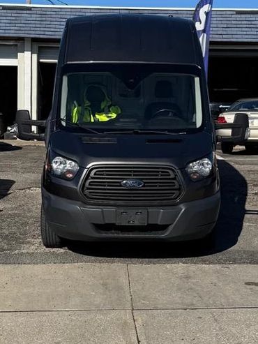 Cars and a black van parked outside a garage under a clear blue sky.