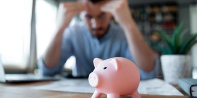 Hombre revisando finanzas con alcancia frente a él