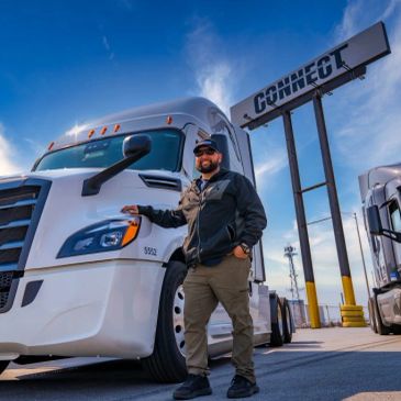 Man standing next to a large white truck under a 'CONNECT' sign.