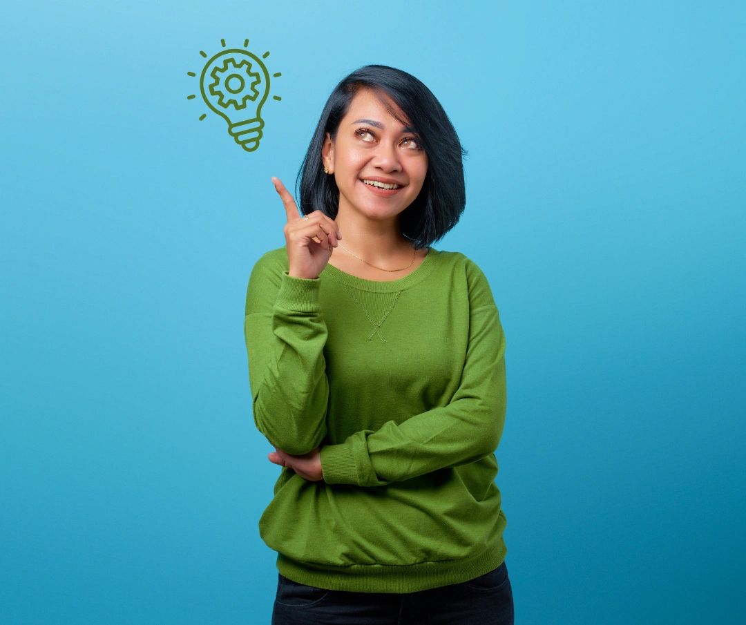 Woman in green sweater pointing at a gear lightbulb symbol, smiling thoughtfully.