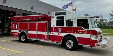 Red and white fire truck parked outside a fire station.