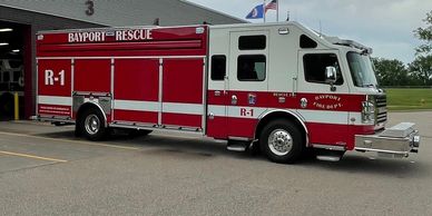A red Bayport Rescue fire truck parked outside a fire station.