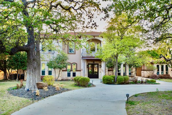a two story home with trees and balcony