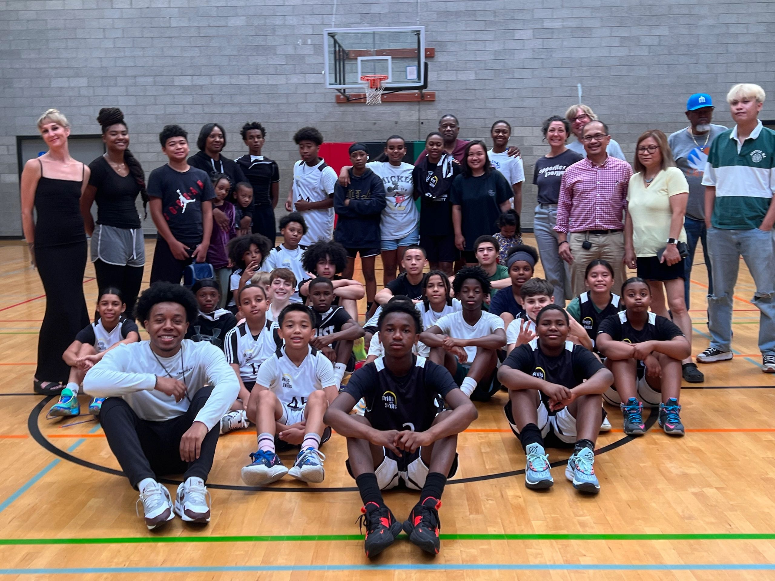 Large group of diverse basketball players and supporters posing in a gym.