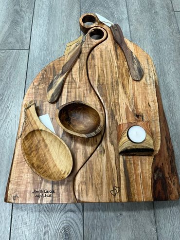 Handcrafted wooden serving set with various utensils and a candle holder.
